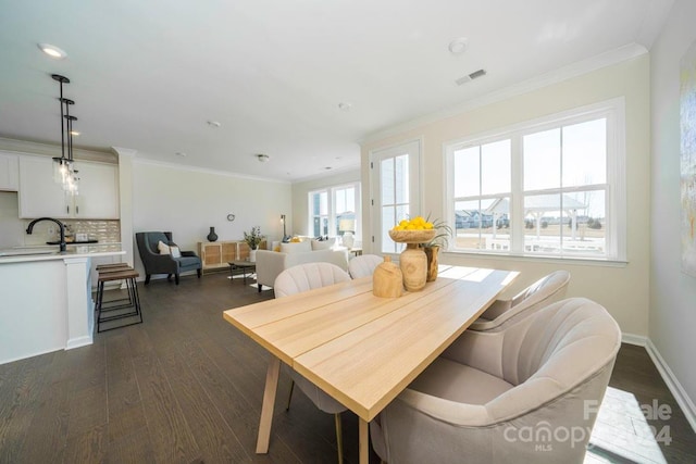 dining space with dark hardwood / wood-style flooring, ornamental molding, and sink