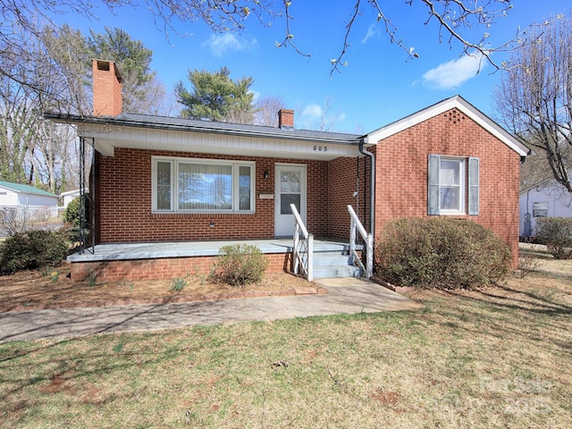 ranch-style house with a front lawn, brick siding, covered porch, and a chimney