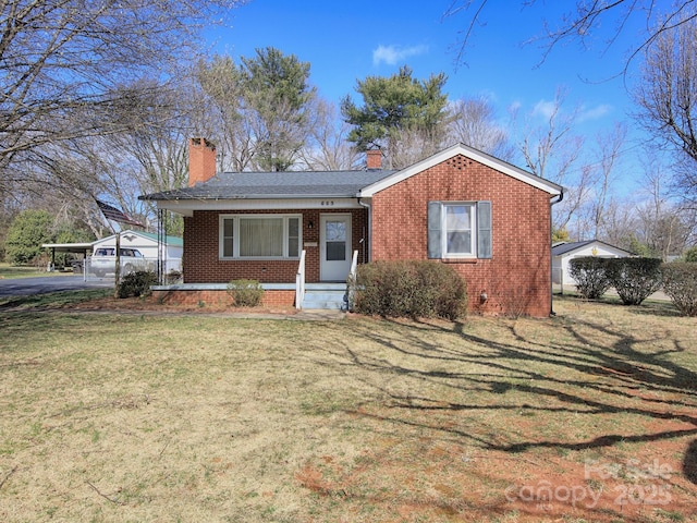 view of front of house featuring driveway, a front lawn, covered porch, brick siding, and a chimney