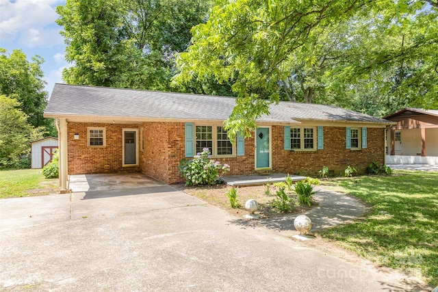 ranch-style home featuring a front lawn and a storage unit