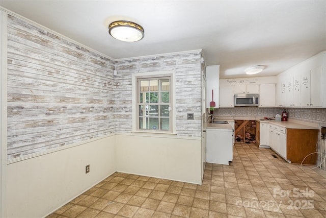 kitchen with decorative backsplash, white cabinetry, sink, and kitchen peninsula