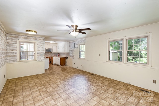 kitchen featuring decorative backsplash, white cabinets, a healthy amount of sunlight, and ceiling fan