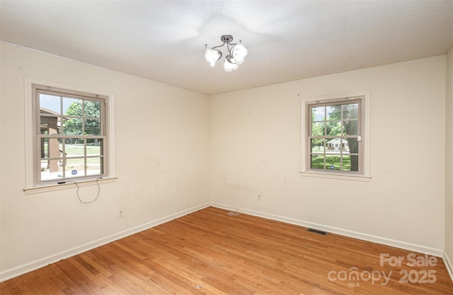 empty room with a notable chandelier and hardwood / wood-style flooring