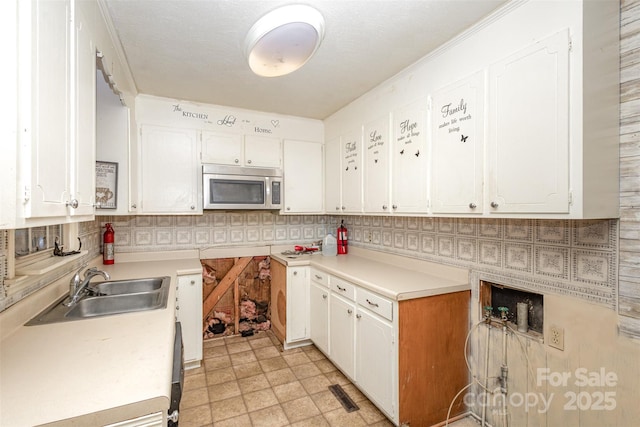 kitchen with white cabinets, backsplash, crown molding, and sink