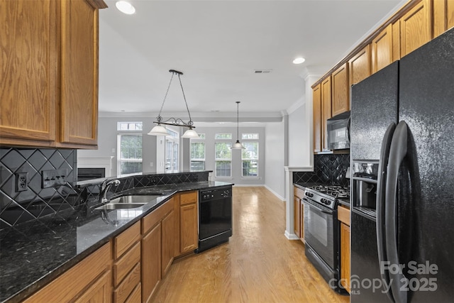 kitchen with decorative backsplash, sink, black appliances, pendant lighting, and light hardwood / wood-style floors