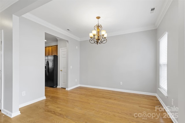 spare room with ornamental molding, light hardwood / wood-style flooring, and an inviting chandelier