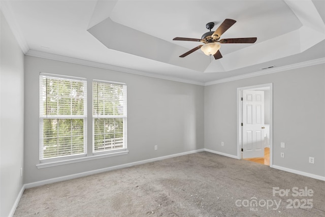 carpeted spare room with ceiling fan, crown molding, and a tray ceiling