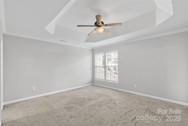 carpeted empty room featuring a raised ceiling, ceiling fan, and ornamental molding