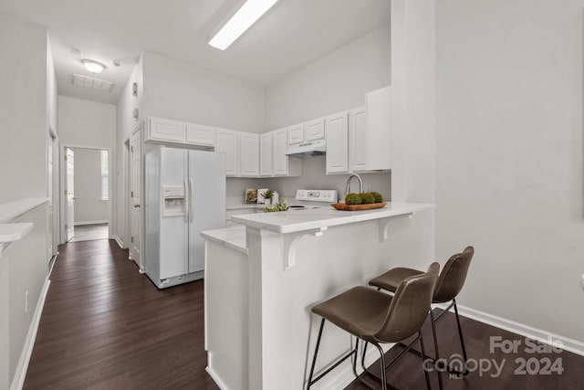 kitchen featuring a kitchen bar, white cabinetry, kitchen peninsula, white refrigerator with ice dispenser, and dark hardwood / wood-style flooring