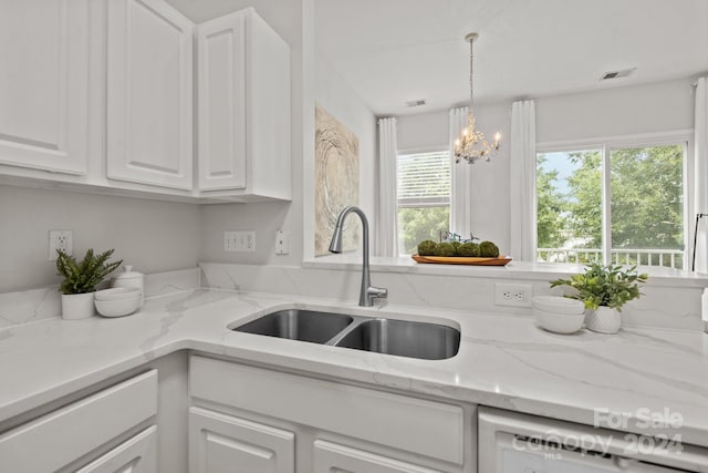 kitchen with white cabinets, dishwashing machine, light stone counters, and sink