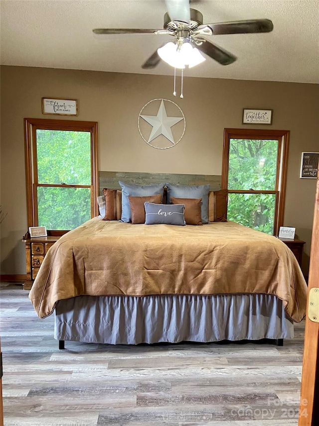 bedroom featuring hardwood / wood-style floors, ceiling fan, a textured ceiling, and multiple windows