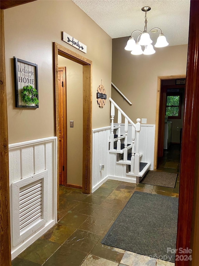 foyer entrance featuring a textured ceiling and an inviting chandelier