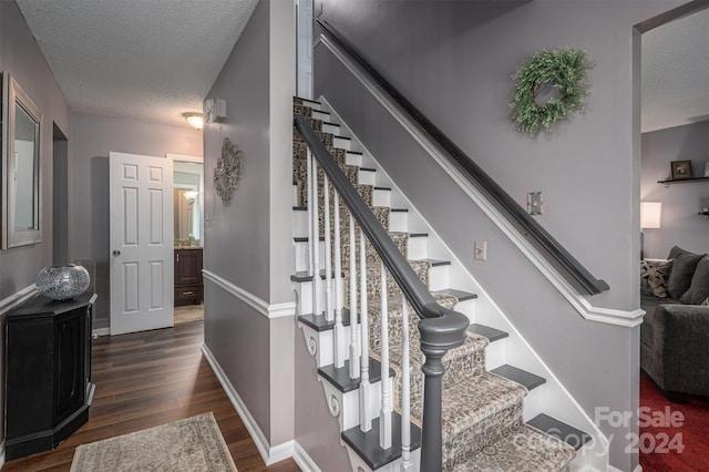 stairway with wood-type flooring and a textured ceiling