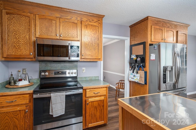 kitchen with dark wood-type flooring, a textured ceiling, and appliances with stainless steel finishes