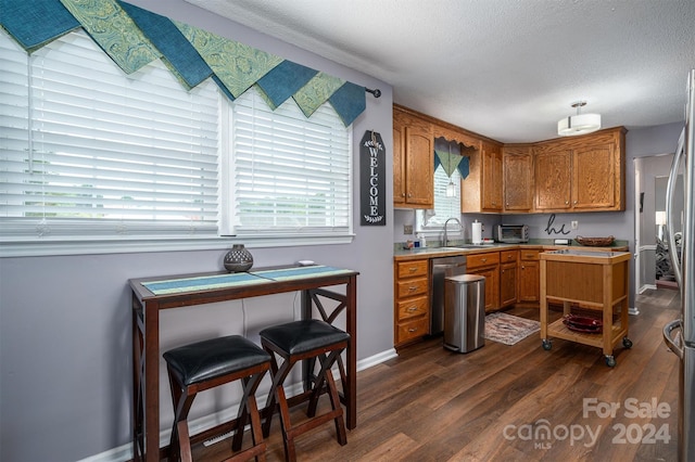 kitchen featuring a textured ceiling, dark wood-type flooring, dishwasher, and sink