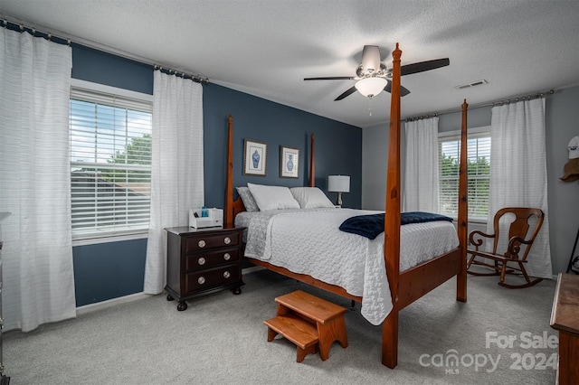 carpeted bedroom featuring ceiling fan and a textured ceiling