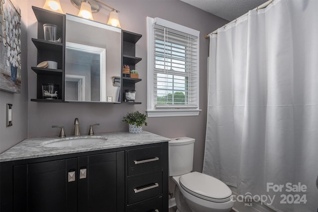 bathroom with a textured ceiling, toilet, and vanity