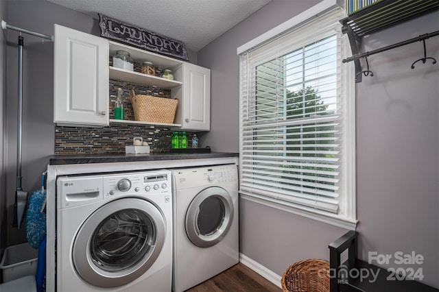 washroom with washing machine and dryer, dark hardwood / wood-style floors, a textured ceiling, and cabinets