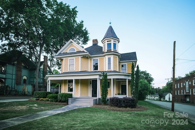 victorian house featuring covered porch and a front lawn