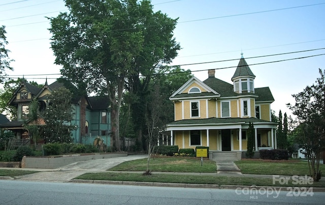 victorian-style house featuring a front lawn and covered porch