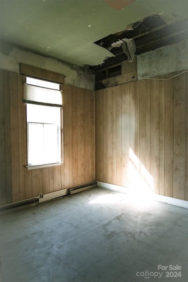 empty room with wood walls and concrete flooring