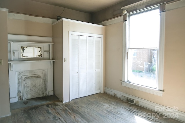 unfurnished bedroom featuring a closet, a fireplace, and dark hardwood / wood-style floors