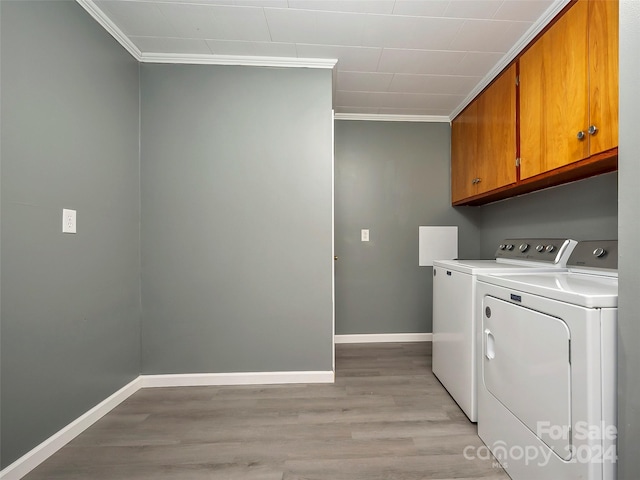 laundry area with cabinets, light wood-type flooring, separate washer and dryer, and ornamental molding