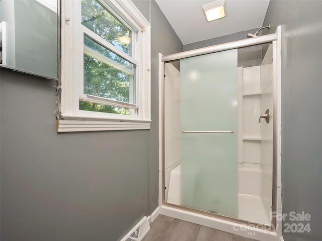 bathroom with hardwood / wood-style flooring and a shower with shower door