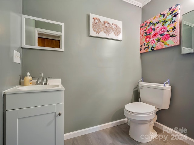 bathroom with hardwood / wood-style floors, vanity, toilet, and ornamental molding