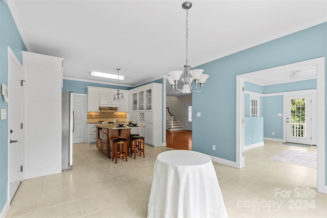 tiled dining space with ceiling fan with notable chandelier and ornamental molding