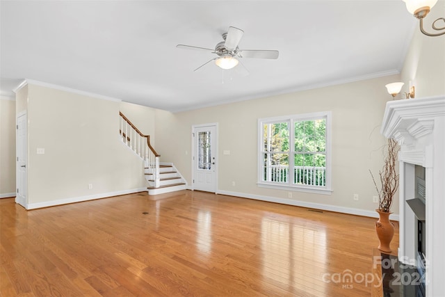 unfurnished living room with ceiling fan, light wood-type flooring, and ornamental molding