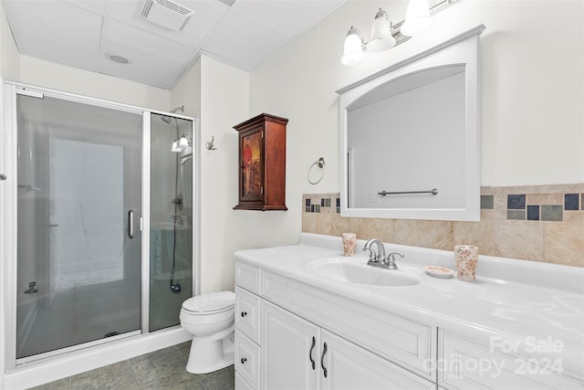 bathroom with tile patterned floors, a drop ceiling, vanity, toilet, and a shower with shower door