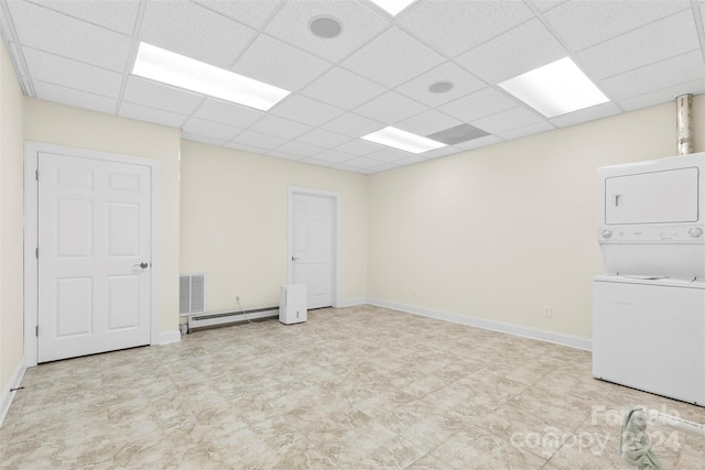 interior space with a paneled ceiling, stacked washer and dryer, and a baseboard radiator