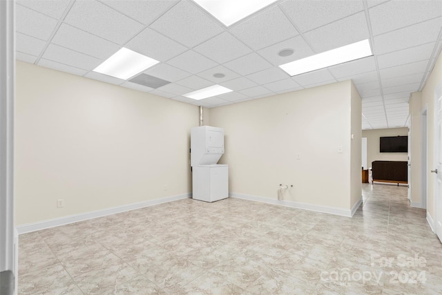 empty room with stacked washer / dryer and a drop ceiling