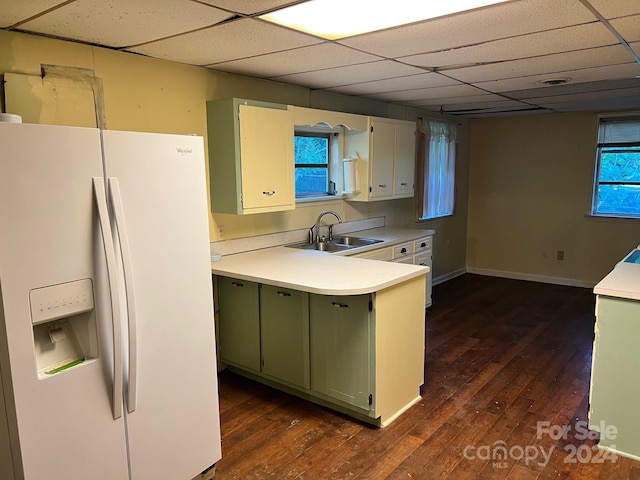 kitchen featuring a drop ceiling, dark wood-type flooring, sink, white fridge with ice dispenser, and green cabinets