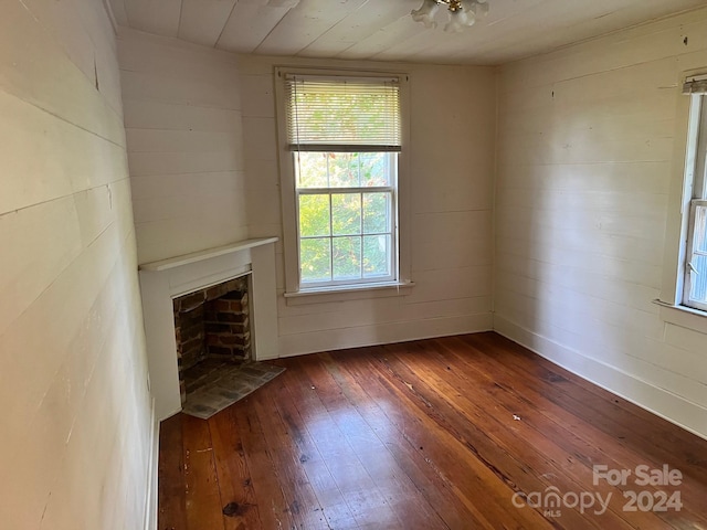 unfurnished living room with dark hardwood / wood-style floors and wood walls