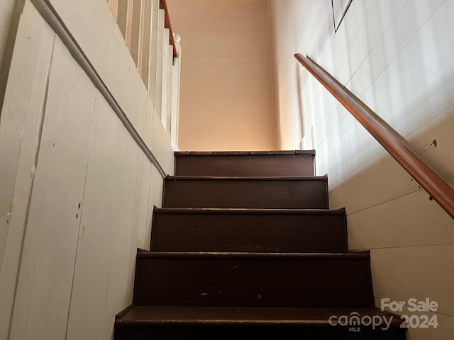 staircase featuring wooden walls