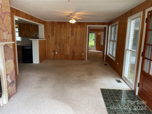 unfurnished living room featuring ceiling fan, wooden walls, carpet, and a textured ceiling