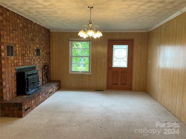 unfurnished living room featuring carpet floors, ornamental molding, a textured ceiling, and a wood stove