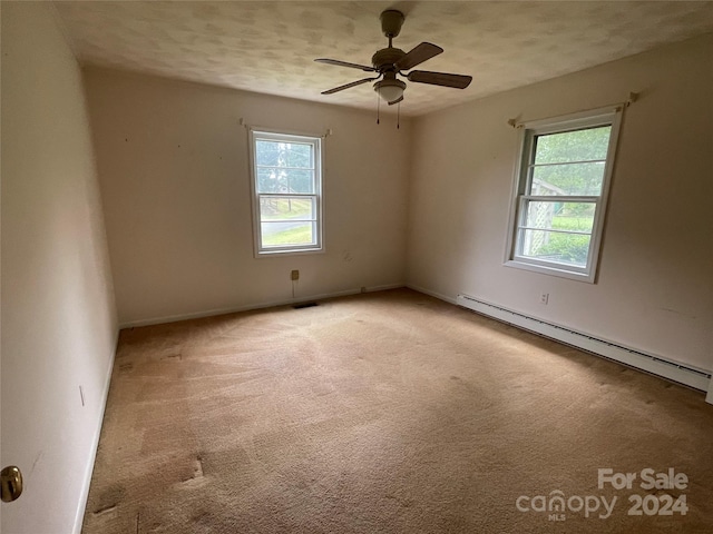 spare room with ceiling fan, light colored carpet, a textured ceiling, and a baseboard heating unit