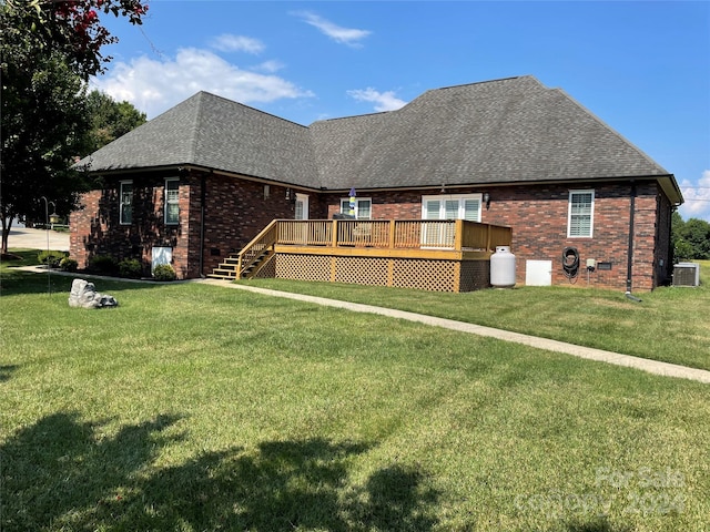 rear view of house featuring central AC, a wooden deck, and a lawn