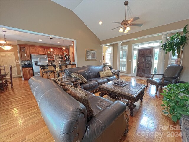 living room featuring vaulted ceiling, a wealth of natural light, and ornate columns