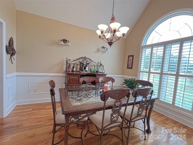 dining space featuring vaulted ceiling, a wealth of natural light, a chandelier, and light hardwood / wood-style flooring