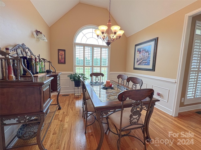 dining room featuring light wood-type flooring, vaulted ceiling, and a notable chandelier