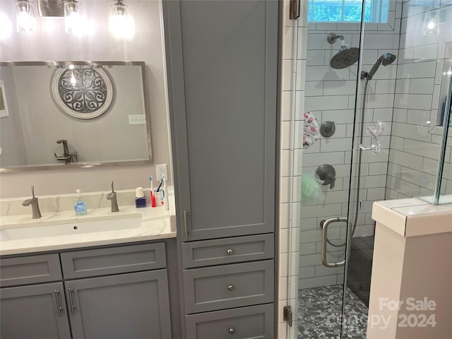 bathroom featuring a shower with shower door and vanity