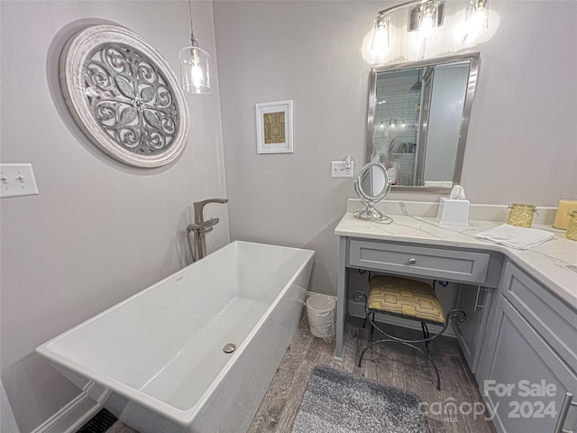 bathroom featuring a freestanding bath, wood finished floors, and vanity