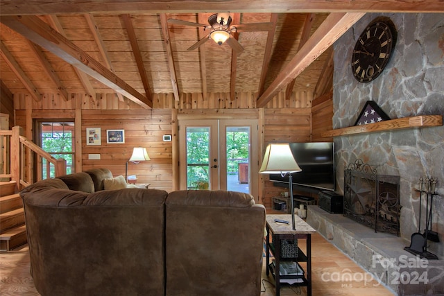 living room with ceiling fan, wooden ceiling, a stone fireplace, wooden walls, and light wood-type flooring