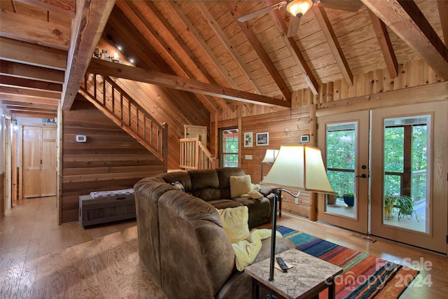 living room with wood-type flooring, beam ceiling, french doors, and wood walls