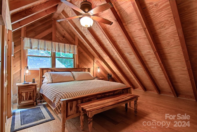 bedroom featuring lofted ceiling with beams, hardwood / wood-style flooring, ceiling fan, and wood walls