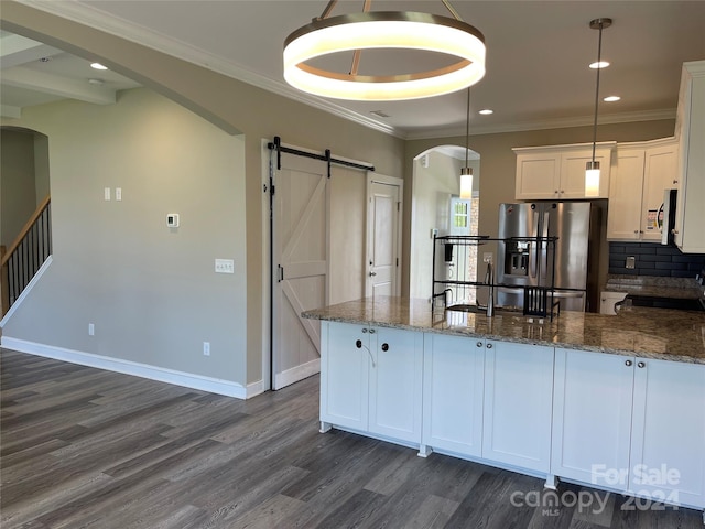 kitchen featuring decorative light fixtures, white cabinetry, a barn door, dark stone countertops, and stainless steel appliances